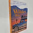 Bucheinbandtext: "Über Mut, Abenteuer und ein Leben voller Freiheit. The Wilder Way. Eva zu Beck." Frau sitzt auf Geländewagen.