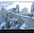 Februar-Kalenderblatt mit verschneiter Steinbrücke und Felsen im Winter, Text: "Im Winter kehrt Ruhe an der Basteibrücke ein".
