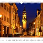 „Abendstimmung am Reichenstrum“, Februar Kalender. Beleuchtete Straße mit historischem Turm im Hintergrund.
