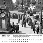 Januar 2027, schwarz-weißes Stadtbild einer belebten Kreuzung mit Menschen in vintage Kleidung, Autos und einem Uhrenturm.