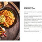 "Wiener Schnitzel mit Meerrettich-Senf." Foto: knuspriges Schnitzel mit Zitronenscheiben, darunter bunte Pommes in kleiner Schale.
