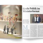 Große Politik im Miniaturformat. Miniaturfiguren klettern über eine Mauer, Soldaten beobachten dies. Foto von zwei Personen.