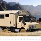 Ein beiger Unimog durchquert Wasser vor einer Gebirgskulisse. Unten ist der Monat Februar abgebildet.