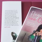 Text: "Manchmal träume ich, wie ich durch den Wald spaziere..." - Steffi Tauber. Cover: "Fliegen war keine Option". Frau mit schwarzem Haar lächelt.