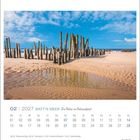 02 | 2027 WATT'N MEER – Kalender mit Holzpfählen im Sand, blauem Himmel und Wolken, reflektiert in einer Wasserpfütze.