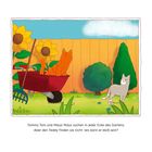 Ein roter Kater sitzt in einer Schubkarre vor einer Holzwand. Ein weiterer Kater steht im Garten. Sonnenblumen im Hintergrund.