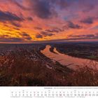 02/2027; Siebengebirge - Blick vom Drachenfels ins Rheintal bei Morgenrot, Fluss, Stadt und Natur unter dramatischem Himmel.