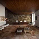 Texte "UMWELT". Raum mit rustikaler Steinwand, Holzboden, modernen Möbeln und dekorativen Kunstwerken.