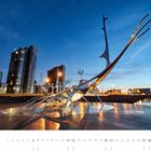 „Sólfar, Reykjavik, Höfuðborgarsvæði“. Eine elegante, moderne Skulptur vor einer städtischen Skyline in der Abenddämmerung.
