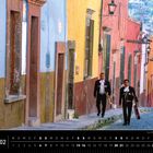 Text: "Mexiko 02", darunter ein Monatskalender. Zwei Männer in traditioneller Kleidung gehen eine bunte Straße hinunter.