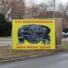 Viel Bundeswehrbung, Krieg wieder trendy. Illustration eines stilisierten Gesichts auf gelbem Hintergrund an einer Straße.