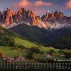 St. Magdalena, Villnößtal (Italien). Kalender mit Datumsangaben. Berge leuchten im Abendlicht über grünen Tälern und Häusern.