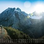 Kalender mit den Tagen 1 bis 28 und Monat 2. Radfahrer auf Bergpfad, im Hintergrund schroffe Berggipfel und Sonnenstrahlen.