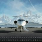 Monatskalender mit Zahlen und Wochentagen. Ein Flugzeug steht auf einer Landebahn vor schneebedeckten Bergen.
