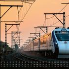 Zug mit der Anzeige „Solapur Jn“ auf nebliger Gleisstrecke, im Hintergrund Stromleitungen und Bäume; Kalender am unteren Rand.