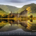 Kalender mit Burgruine Kilchurn. Gebäude und Bäume spiegeln sich in einem stillen See, umgeben von grünen Hügeln.