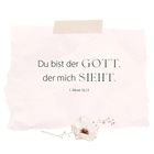 Text: "Du bist der GOTT, der mich SIEHT. 1. Mose 16,13." Darunter eine zarte Blume auf hellem Hintergrund.