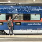 Ein Mann zeigt auf einen blauen Zug mit den großen, weißen Schriftzügen "nightjet" und "couchette".