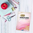 "Wow! SCHULPLANER 2026/27" steht auf einem bunt gestalteten Planer auf einem hellen Holzuntergrund mit Schulsachen.