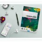Text: "Der Schulplaner 2026/27" auf einem farbenfrohen Notizbuch. Daneben sind ein Smartphone, Kopfhörer und Büromaterial.