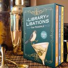 "A Library of Libations" von Tim Federle auf einer Box mit Vogel und Cocktailglas. Daneben ein Cocktailshaker und -löffel.