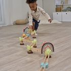 Ein Kind spielt auf dem Holzboden mit einer bunten Holzspielzeugkugelbahn in einem gemütlichen Raum.