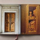 Ein aufgeschlagenes Buch zeigt links eine kunstvolle Holztür und rechts ein illusionistisches Gemälde eines Bücherregals.