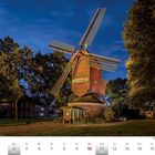 Text "Narrenmühle" an einer beleuchteten, farbenfrohen Windmühle, umgeben von Bäumen, mit Oktober-Kalenderdaten unten.