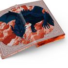 Ein offenes Buch zeigt eine Illustration. Ein blau-schwarzer Drache erhebt sich aus rot-orangefarbenen Wolken.