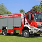 Text: "Freiwillige Feuerwehr Stadt Landshut" und "Feuerwehr". Ein rotes Feuerwehrauto steht auf einem grünen Rasen.
