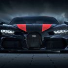 Ein schwarzer Sportwagen mit rotem Streifen und leuchtenden Scheinwerfern von vorn, Bugatti-Logo vorne.