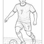 Nummer 7 auf Trikot und Shorts. Ein Fußballspieler dribbelt auf Gras, konzentriert in Aktion. 