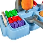 Eine blaue Spielküche mit Plastikinhalten: grüne, rote, und violette Formen. Eine graue Pfanne und ein Brötchen sind sichtbar.