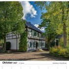 Oktober 2027, 41. Woche. Heimathaus in Ense-Bremen. Fachwerkhaus umgeben von Bäumen und blauem Himmel.