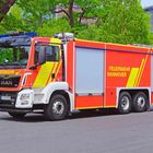 Rotes Feuerwehrauto mit der Aufschrift "FEUERWEHR HANNOVER" auf der Seite, in städtischer Umgebung.