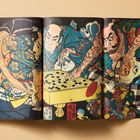 Japanische Schriftzeichen in roten und grünen Kästen. Illustration von Männern in farbenfrohen Roben beim Go-Spiel.