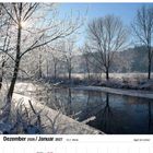 Dezember 2026/Januar 2027 Kalender. Winterliche Flusslandschaft bei Sonnenschein, vereiste Bäume spiegeln sich im Wasser.