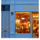 Zahlen 13 und 18, "ACHATS VENTES", "ANTIQU", Kalender unten, 7. bis 13. Juni 2027, blaue Fassade, Schaufenster mit Antiquitäten.