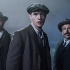 Drei Männer in historischer Kleidung, mittlerer Mann trägt eine Mütze. Die Atmosphäre ist neblig und dunkel.