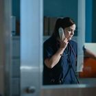 Eine Frau in medizinischer Kleidung telefoniert an einem Schalter, ein Stethoskop um den Hals.