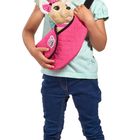 Ein fröhliches Kind in Jeans hält ein Plüschtier mit pinker Tasche.