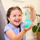 Ein lachendes Kind in blauem Shirt spielt fröhlich mit zähem, blauem Schleim in seinen Händen.