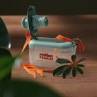 „Scout“ steht auf einer durchsichtigen Box mit Deckel, Linsen, orangenen Riemen und Pflanzen im Vordergrund.