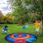 Zwei Kinder spielen im Park auf einer Zielmatte mit Punkten, die Zahlen wie 20, 30 und 50 zeigt.