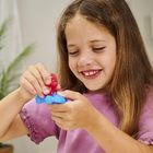 Ich sehe keinen Text. Ein Kind spielt lächelnd mit buntem Spielzeug. Im Hintergrund sind Pflanzen und eine Lampe.