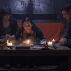 Text „BLOC“ an einer Metalltür. Drei Personen feiern um einen Tisch mit Kerzen und einer Geburtstagstorte.