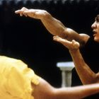 Zwei Personen in einer Kampfszene, eine trägt Gelb, die andere Schwarz, zeigen dynamische Kampfhaltungen.