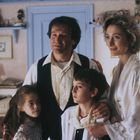 Eine Familie steht zusammen in einem gemütlich dekorierten Raum. Ein Mann, eine Frau und zwei Kinder lächeln.