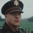 Mann in Uniform mit fünf Sternen und Adleremblem, im Freien, nachdenklicher Blick, Hintergrund unscharfe Wiese.