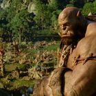 Ein großer, muskulöser Orc blickt ernsthaft über ein weites Waldgebiet mit primitiven Hütten und rauchenden Feuerstellen.